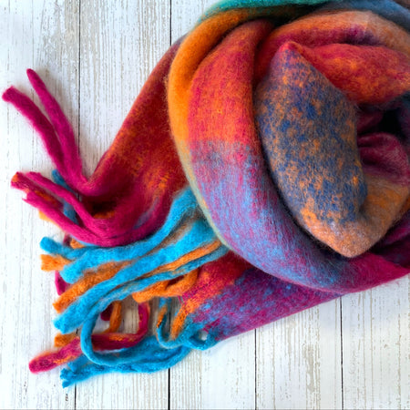 Colourful cosy thick scarf with tassels on a light white wooden surface