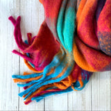 Colourful cosy thick scarf with tassels on a light white wooden surface