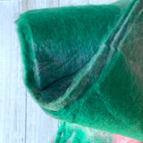 Close up colourful cosy thick scarf with tassels on a light white wooden surface